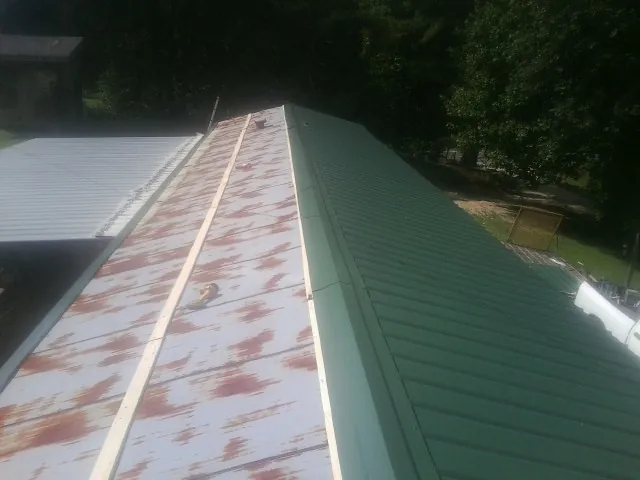 Old rusted panels beside newly installed green metal roofing — Wind Damage Roof Repair by Roofing Brothers in Bowling Green