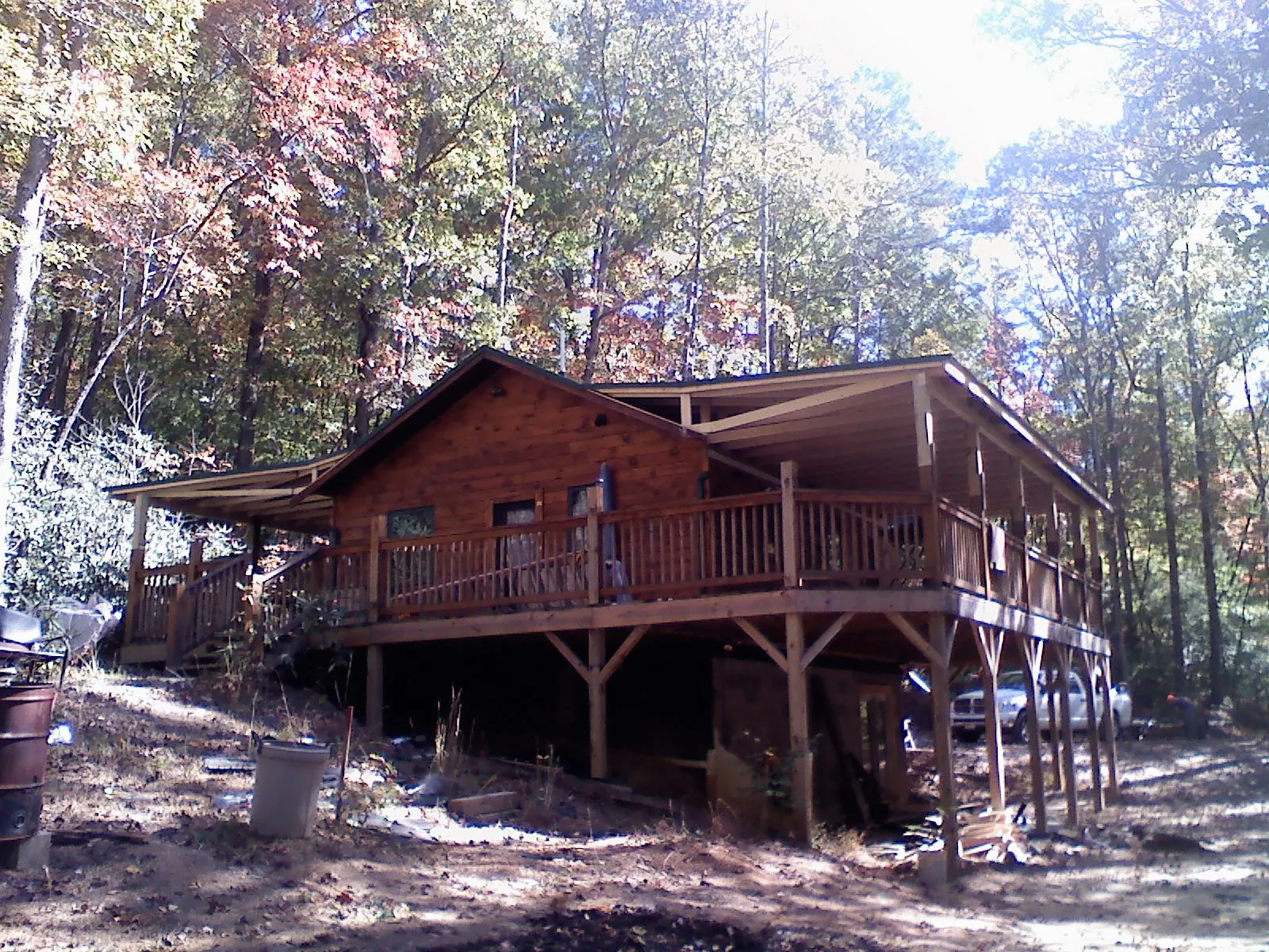 Log cabin with a wraparound porch and metal roof in the fall in Bowling Green