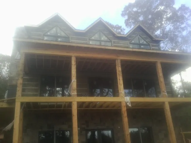 Dormers and porch framing on a large log home under construction — Roof Coating work by our crew in Bowling Green