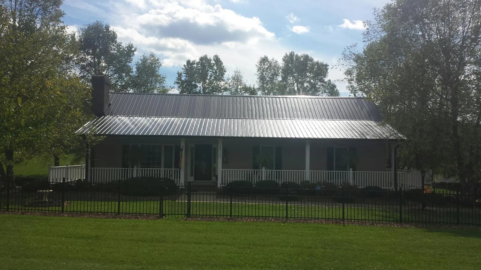 Gray metal roof on a brick ranch with a full width front porch — Gutter Guard Installation work by our crew in Bowling Green